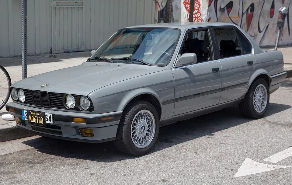 Front three-quarter view of a silver four-door BMW E30 sedan